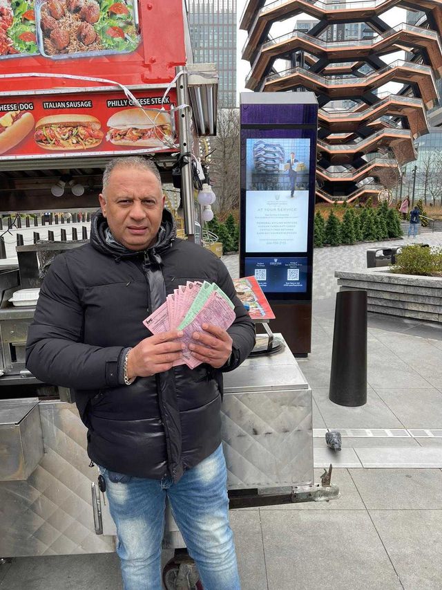 A photo of Mohamed Awad, who sells halal food from a cart on 33rd Street between 10th and 11th Avenue in Manhattan holding up numerous tickets.